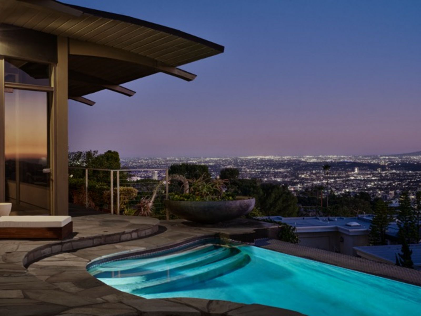 Beleuchteter Swimmingpool auf einer Terrasse mit Blick über die nächtlich erleuchtete Stadt. Im Vordergrund liegt das moderne Wohnhaus, während sich am Horizont ein Lichtermeer ausbreitet. Mittel__26-624_Cole_Pl_-_Nils_Timm_.jpeg