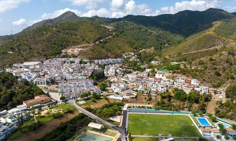 Luftaufnahme eines malerischen andalusischen Dorfes mit dicht stehenden weißen Häusern, schmalen Straßen und einer Kirche. Das Dorf liegt eingebettet zwischen grünen Berghängen, während im Vordergrund ein Fußballplatz und Sportanlagen zu sehen sind. 1500x900_AdobeStock_527241603.jpg