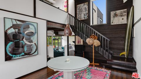 Moderner Flur mit farbigen Kunstbildern, kleinem rundem Beistelltisch, pinkem Teppich und dunkler Holztreppe  origin4.jpeg