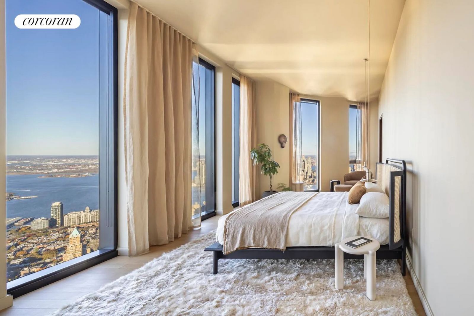 Schlafbereich mit langer bodentiefer Fensterwand, Bett und Stadtblick im Sonnenlicht. 157915551.jpeg