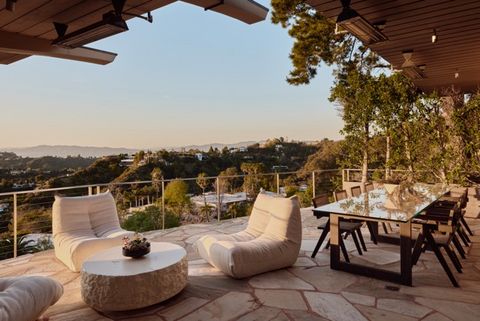 Überdachte Terrasse mit Lounge-Möbeln und großem Esstisch. Die Terrasse blickt auf bewaldete Hügel und die umliegende Wohngegend im warmen Licht der Abendsonne. Mittel__24-624_Cole_Pl_-_Nils_Timm_.jpeg