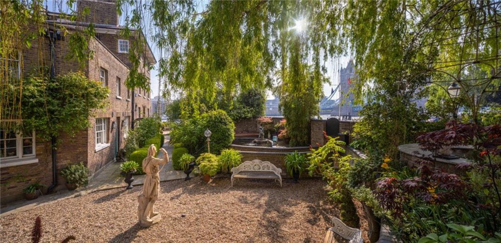 Romantische Gartenecke mit Statue, Boho-Sitzbank und Steinhaus im Hintergrund CHA240006_13.jpg