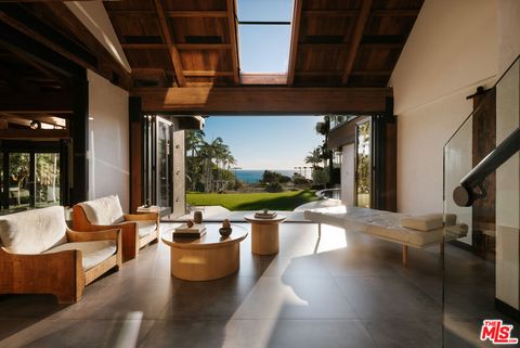 Moderne Sitzecke mit edlen Eichenmöbeln und geöffneter Veranda mit Blick auf Garten und Meer. origin4.jpg