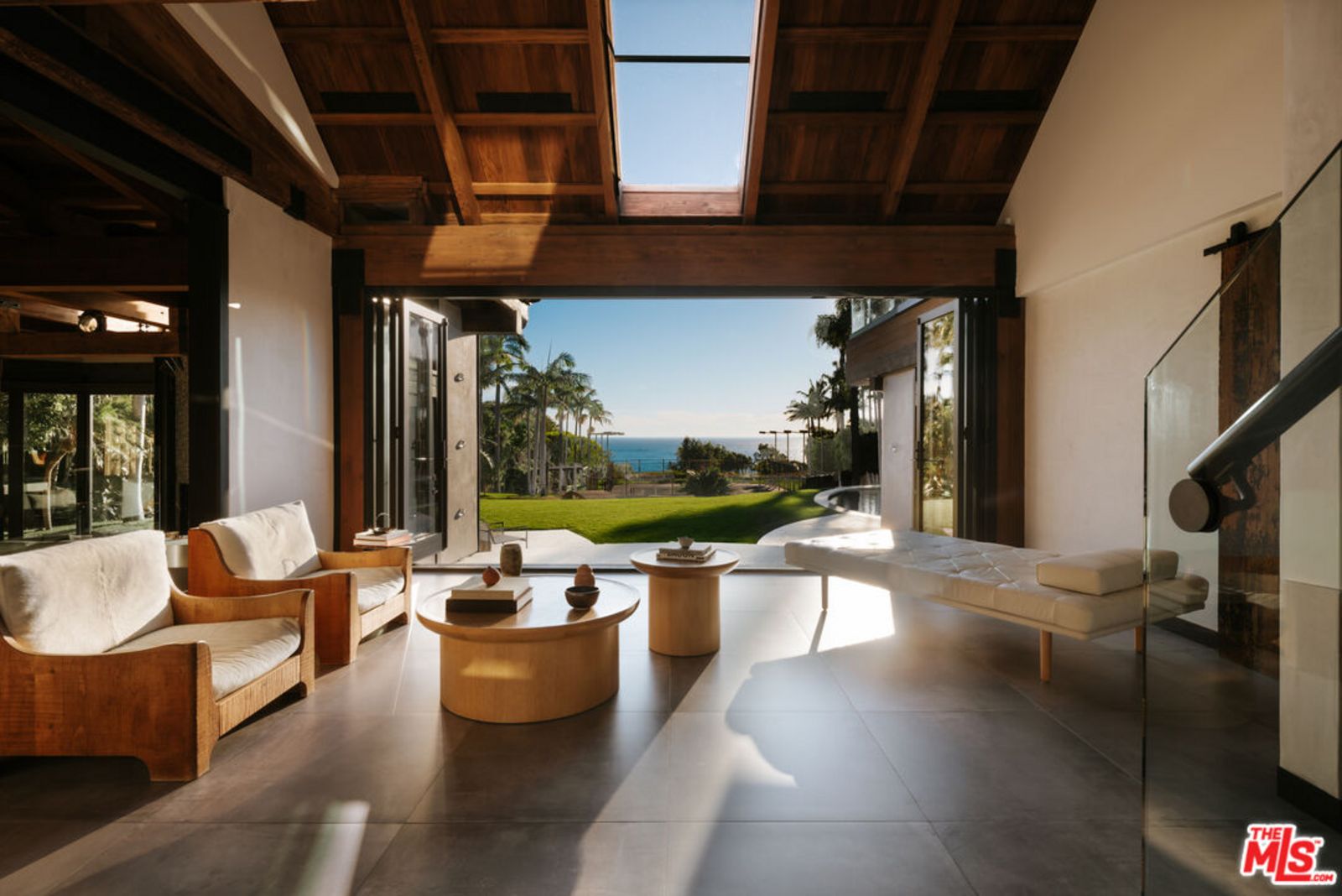 Moderne Sitzecke mit edlen Eichenmöbeln und geöffneter Veranda mit Blick auf Garten und Meer. origin4.jpg