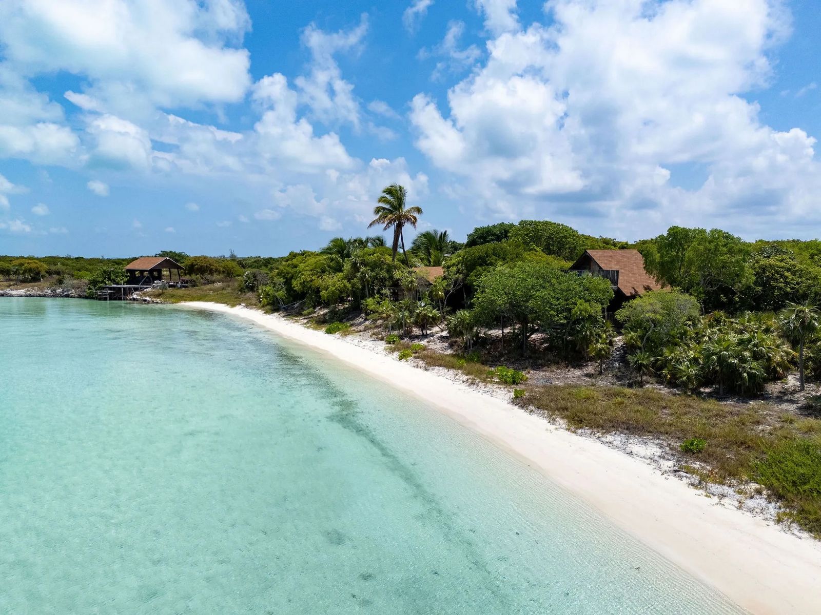 Weißer Sandstrand mit türkisblauem Wasser und grünen Bäumen entlang der Küste. 25278BE5-A735-4164-94B5-0D838DBCD9D1.jpeg