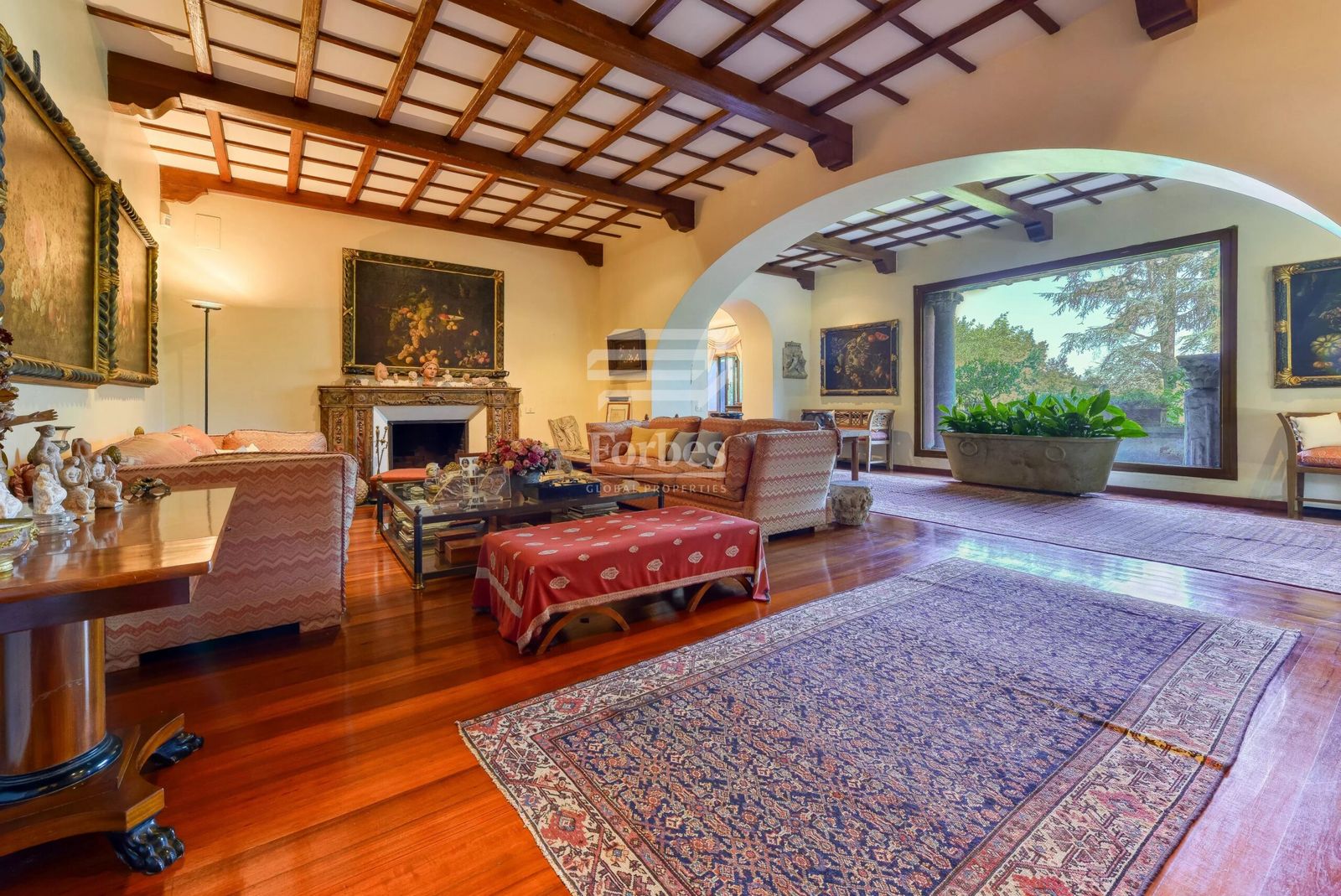 Großes Wohnzimmer mit antikem Kamin, stilvollen Möbelstücken, sichtbaren Holzbalken und Rundbogen zum langen Flur 4a5949fe89899ccb163220d77b9eaee3_7242658232_4096-original-scaled.jpg