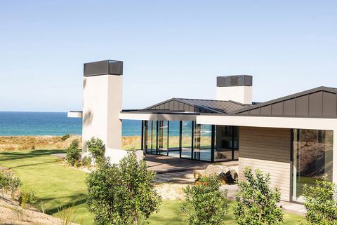 Vom Garten aus sichtbares Haus im Sonnenlicht mit Blick auf das Meer im Hintergrund. Te-Arai-Homesite-11.jpg