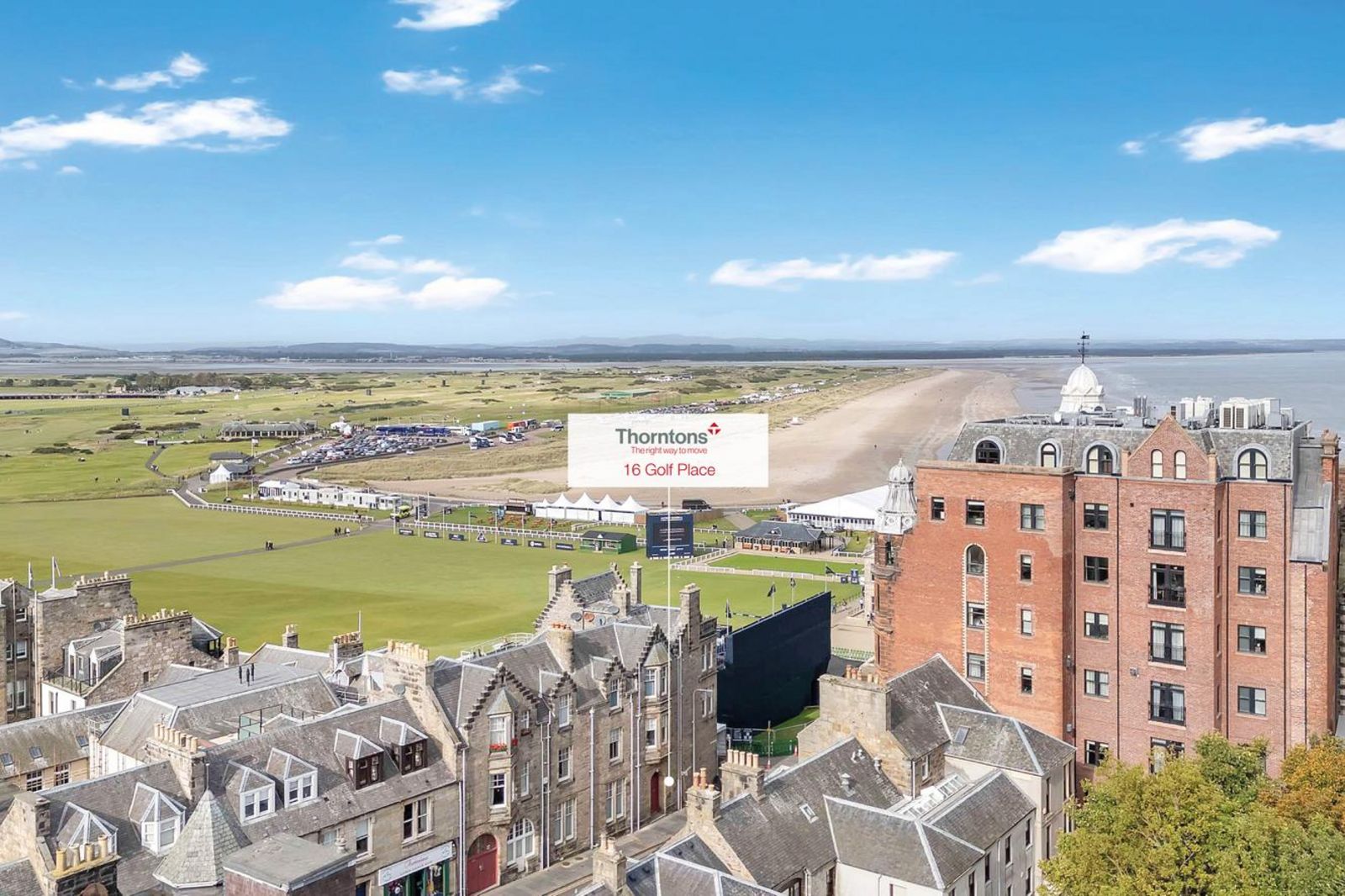 Blick über die Dächer von St Andrews auf den berühmten Golfplatz und die Küstenlandschaft dahinter. Im Vordergrund stehen historische Wohn- und Geschäftshäuser. 53151284.jpg
