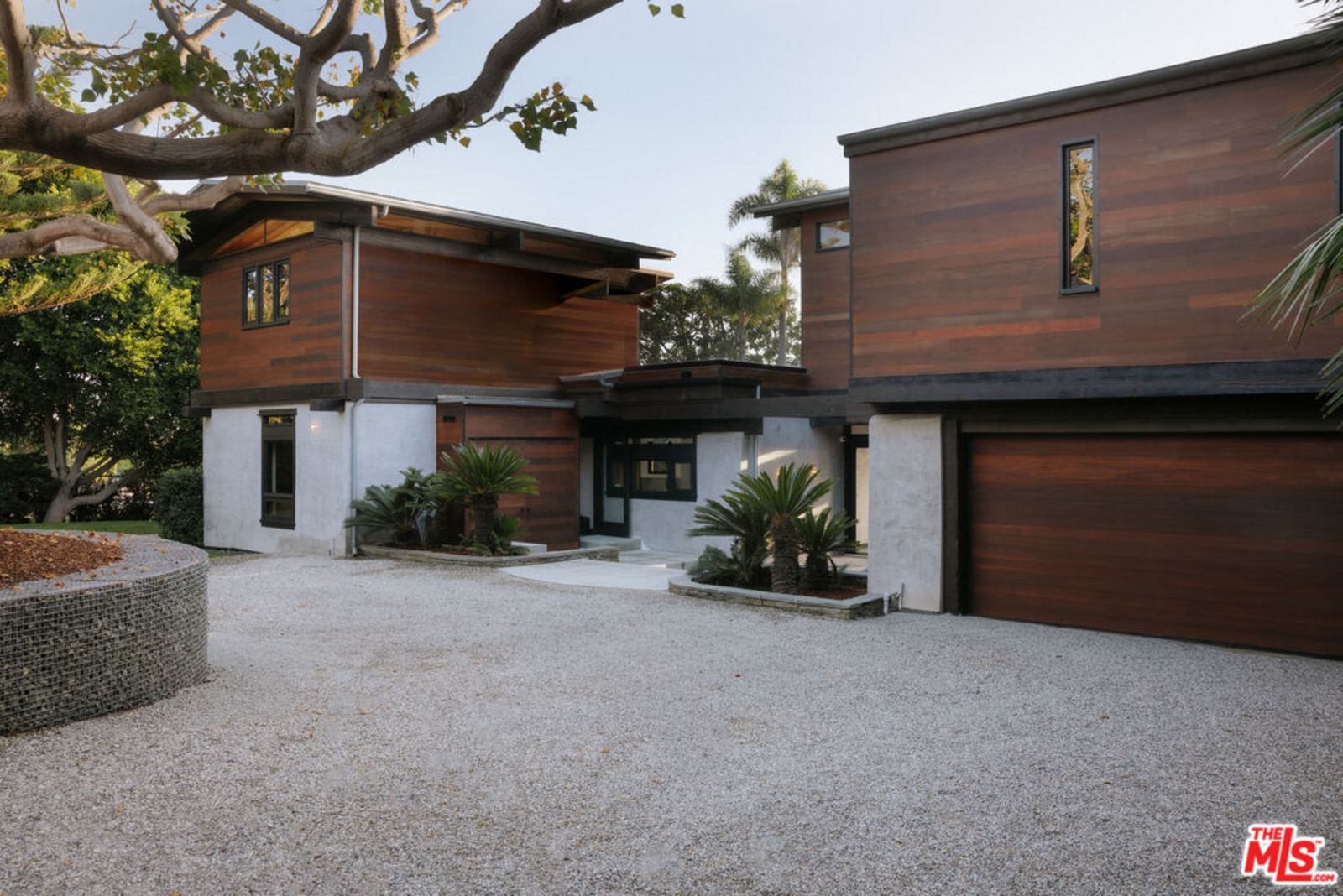 Hausfront aus dunklem Massivholz und grauem Marmor mit kleiner Kiesfläche vor dem Eingang. origin3.jpg