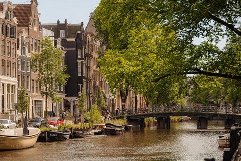 Amsterdamer Kanal bei Tageslicht mit Holzkajaks und einer Brücke voller Fahrräder. 245161446.jpg