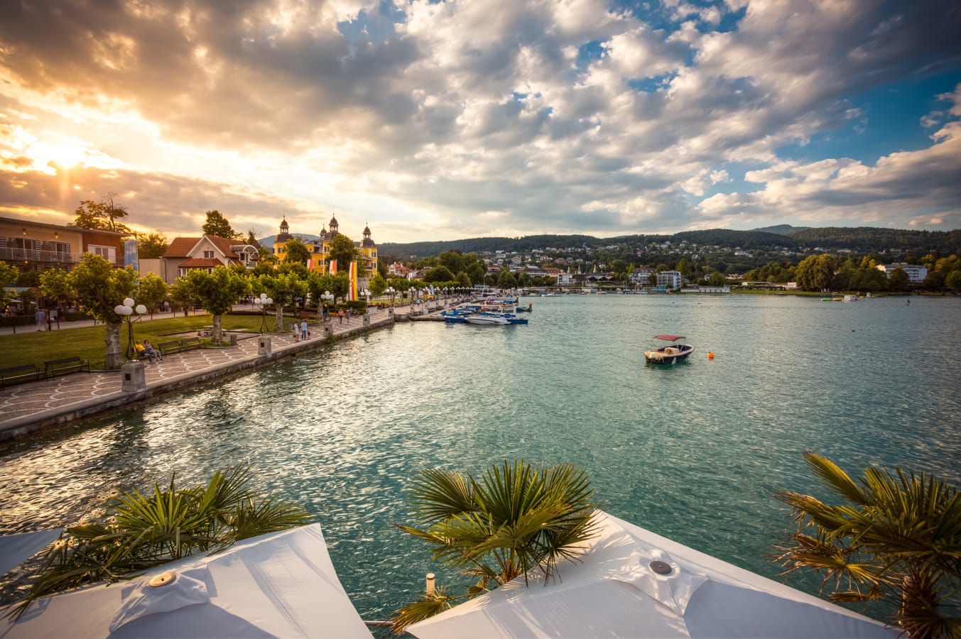 Blick auf den Wörthersee mit türkisblauem Wasser, bewaldeten Ufern und Bergen im Hintergrund bei warmem Licht AdobeStock_386054531_Silke_Koch.jpeg