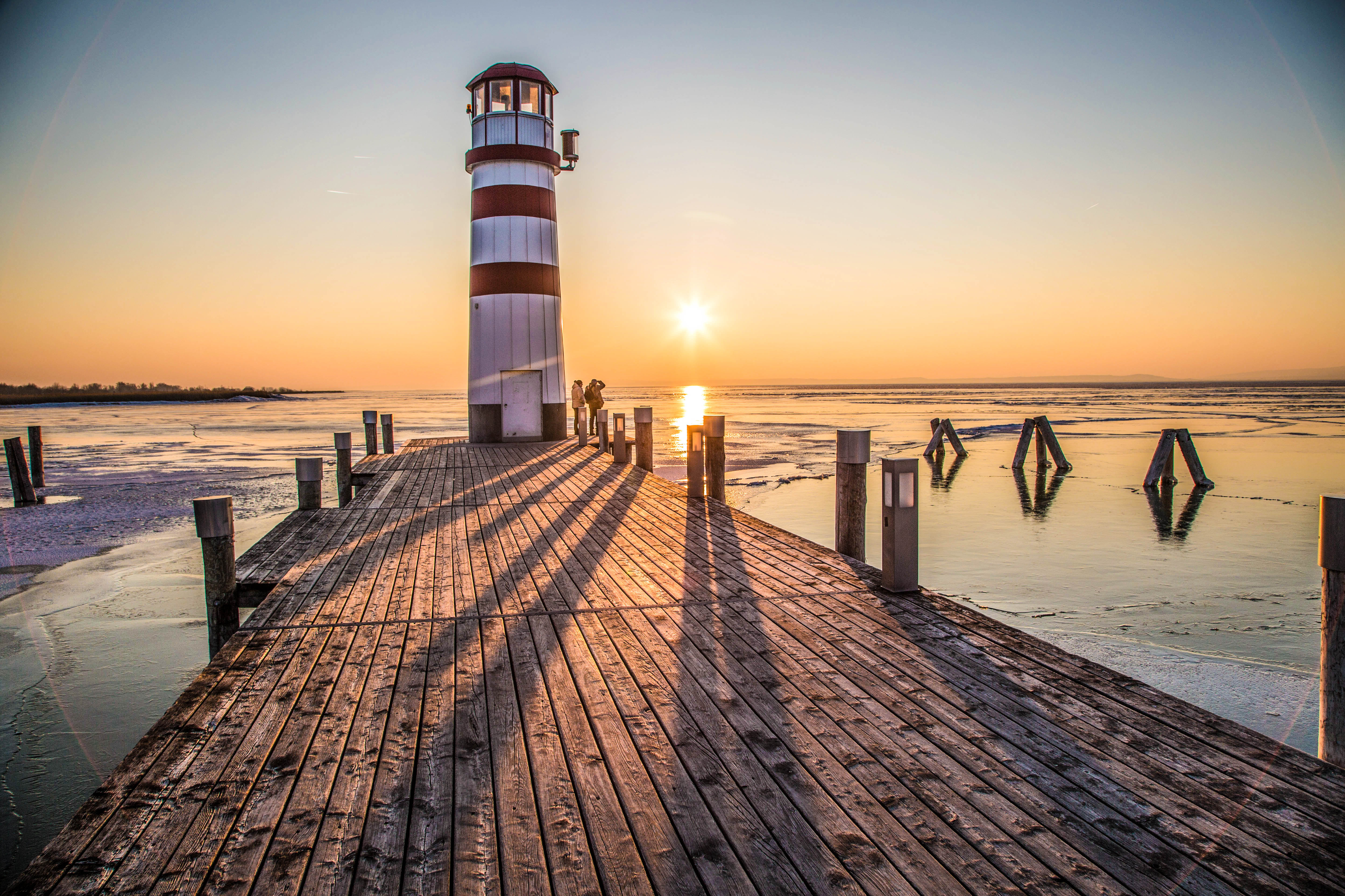 Neusiedlersee, Ansicht eines Leuchtturms auf einem Steg bei Sonnenuntergang AdobeStock_408303453_Schoenbacher_Gerhard.jpeg